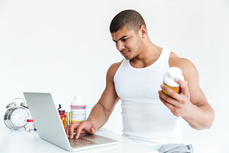 Athlete Using Laptop While Holding Sports Nutrition Supplement