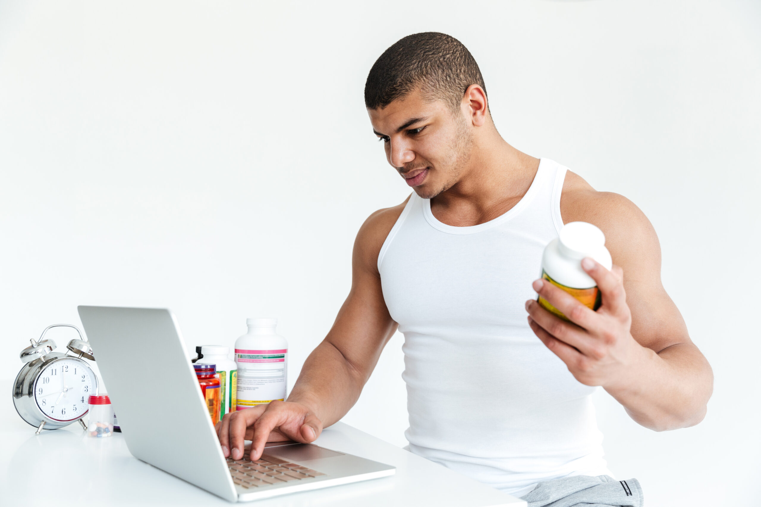 Athlete Using Laptop While Holding Sports Nutrition Supplement